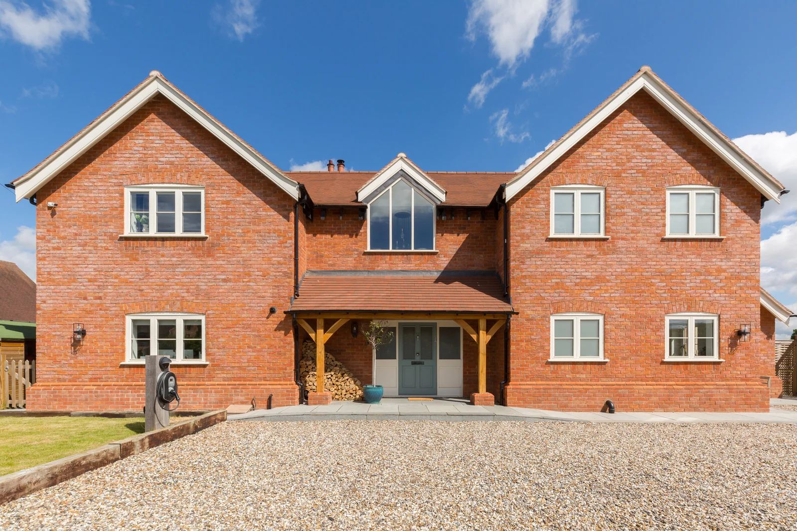 Red brick farmhouse new build with oak porch under a clear sky