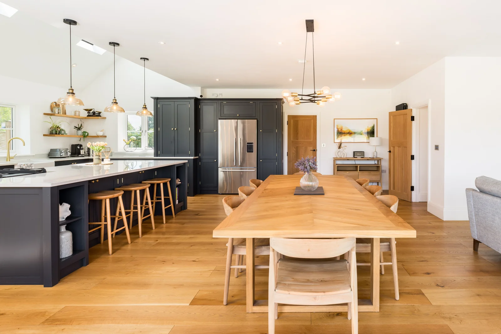 Open plan kitchen and dining room with navy island and long oak table
