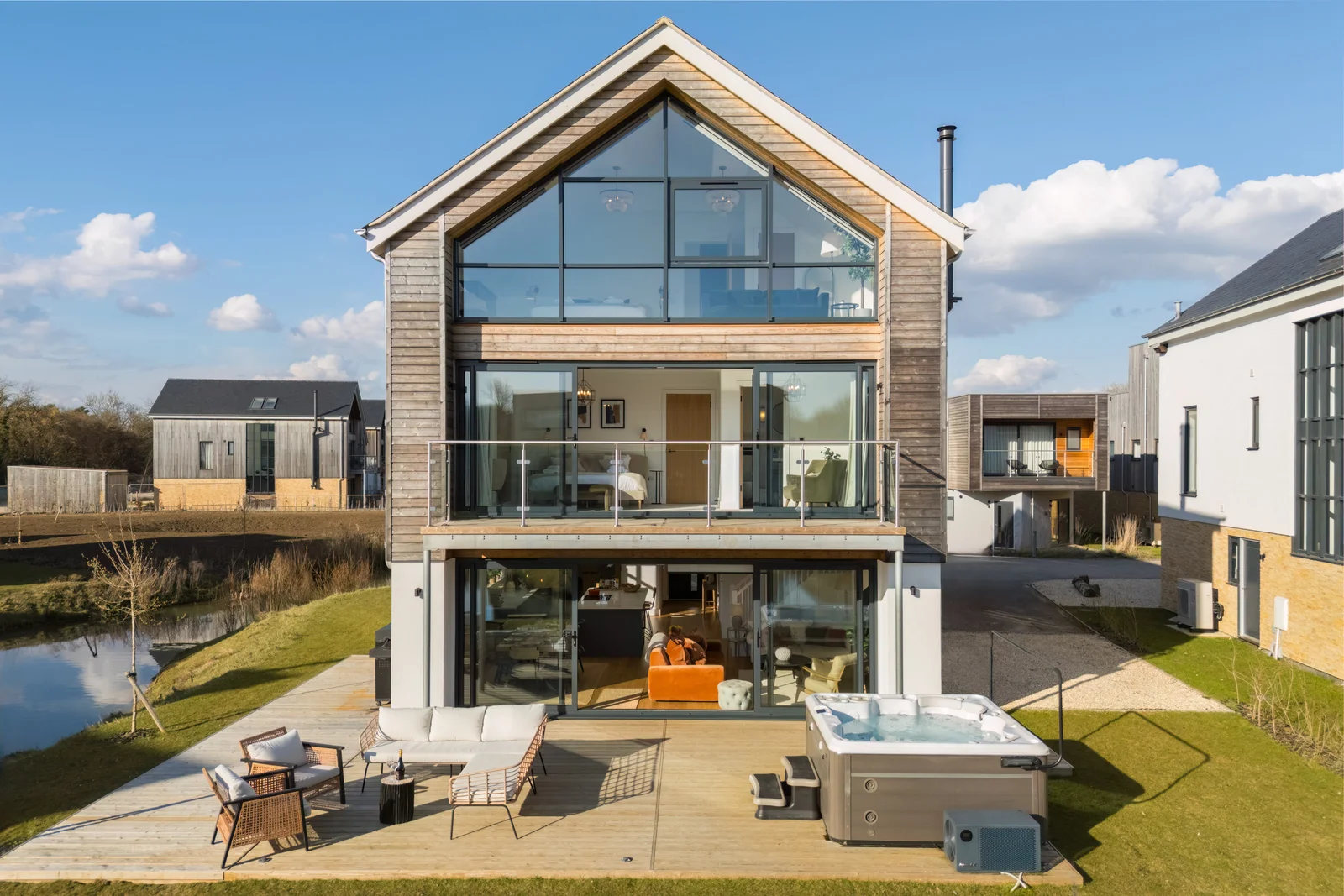 Aerial view of a timber clad lakeside house with terrace and hot tub