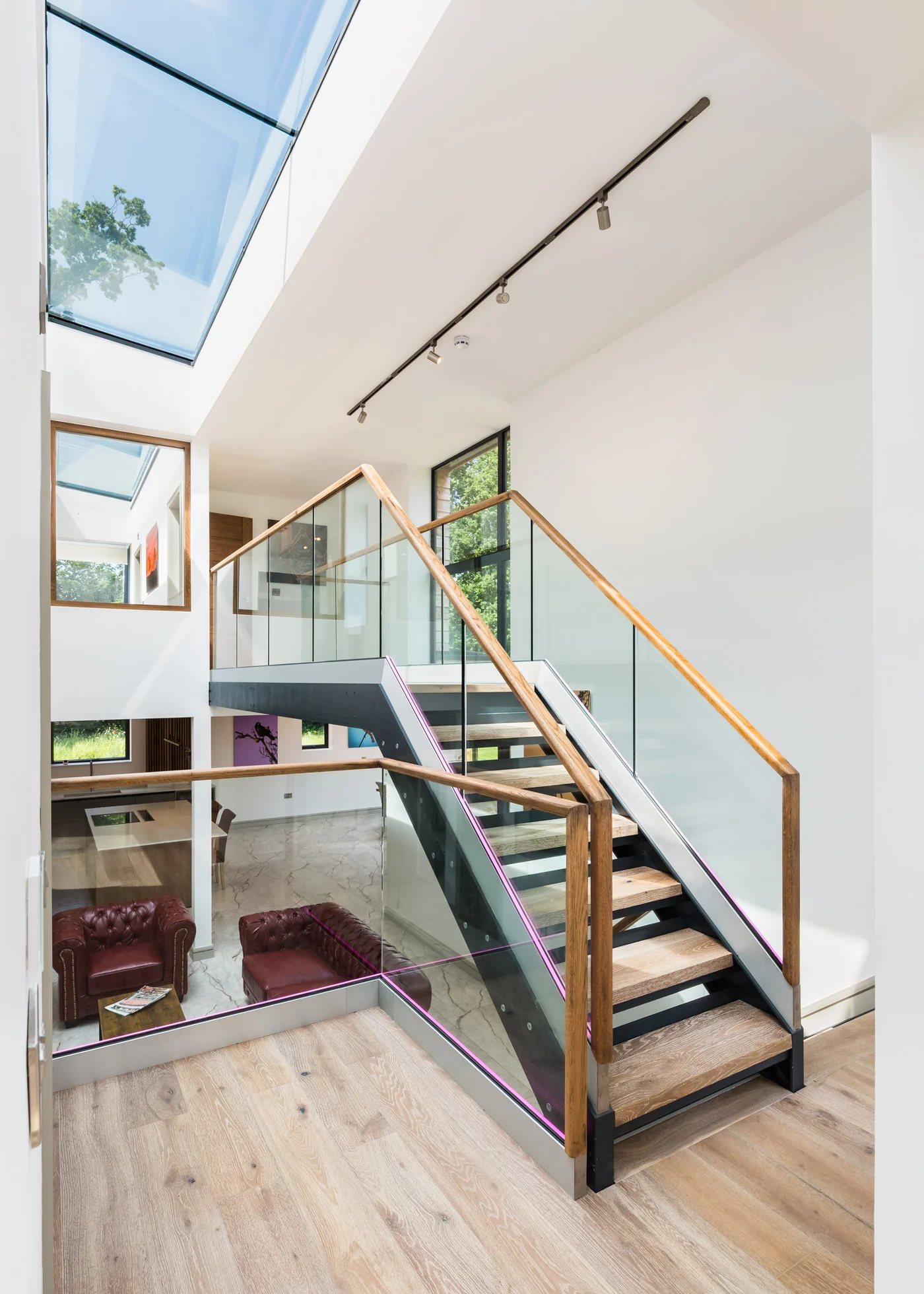 Timber and steel staircase rising beneath a full width rooflight