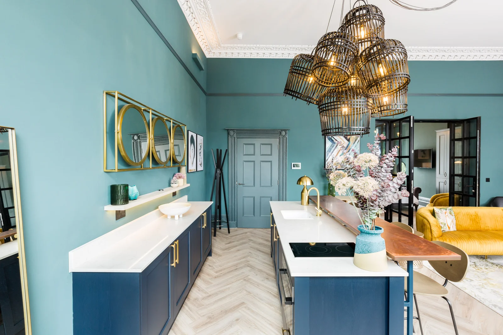 Teal panelled kitchen with white stone island and herringbone floor
