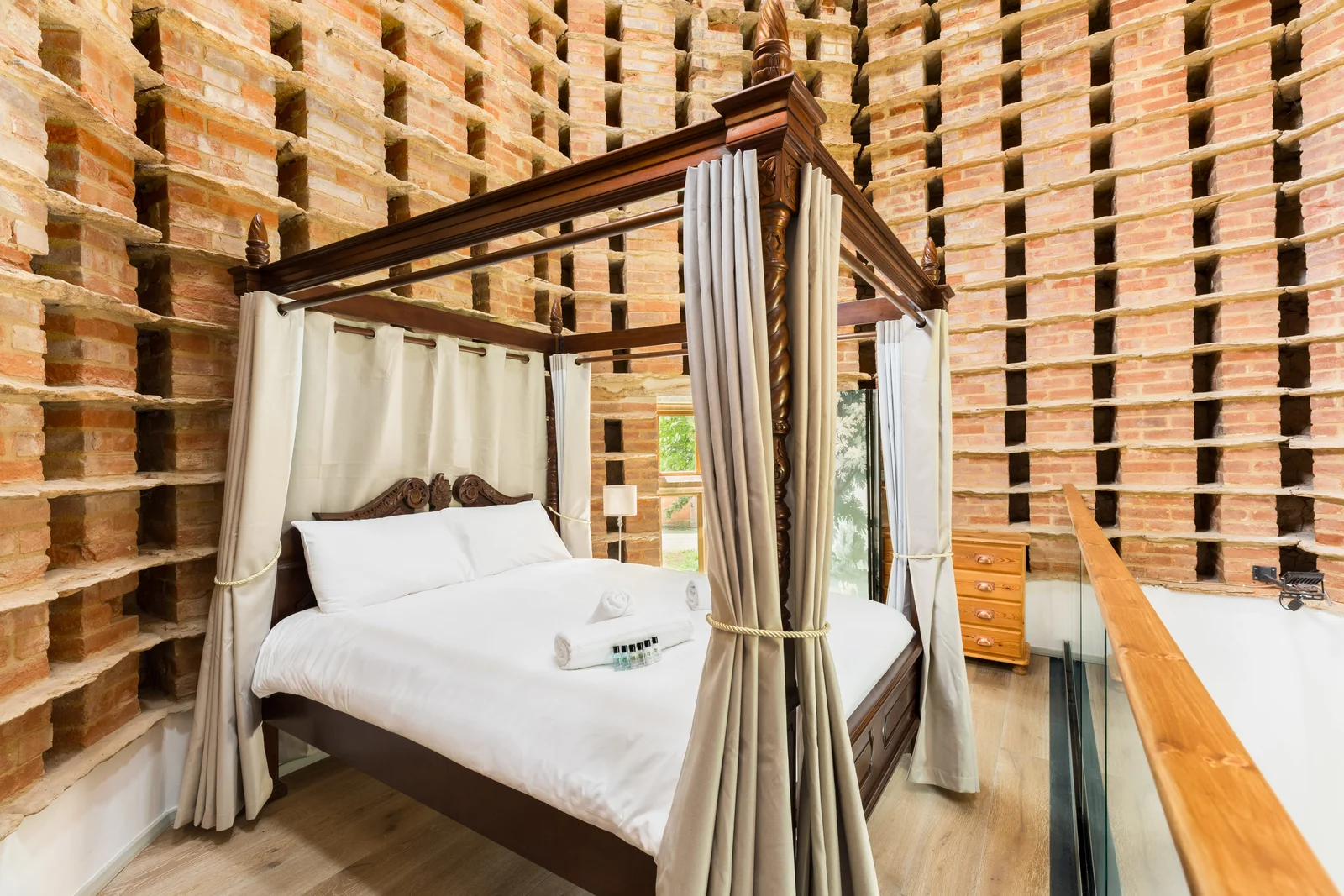 Dark timber four poster bed against a wall of stacked timber