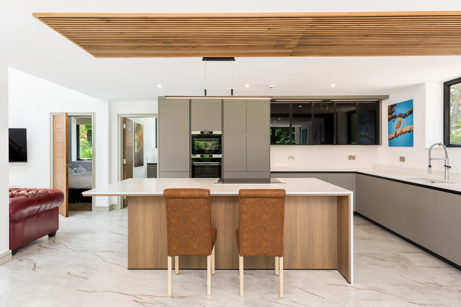 White kitchen beneath a slatted timber ceiling canopy with marble effect floor
