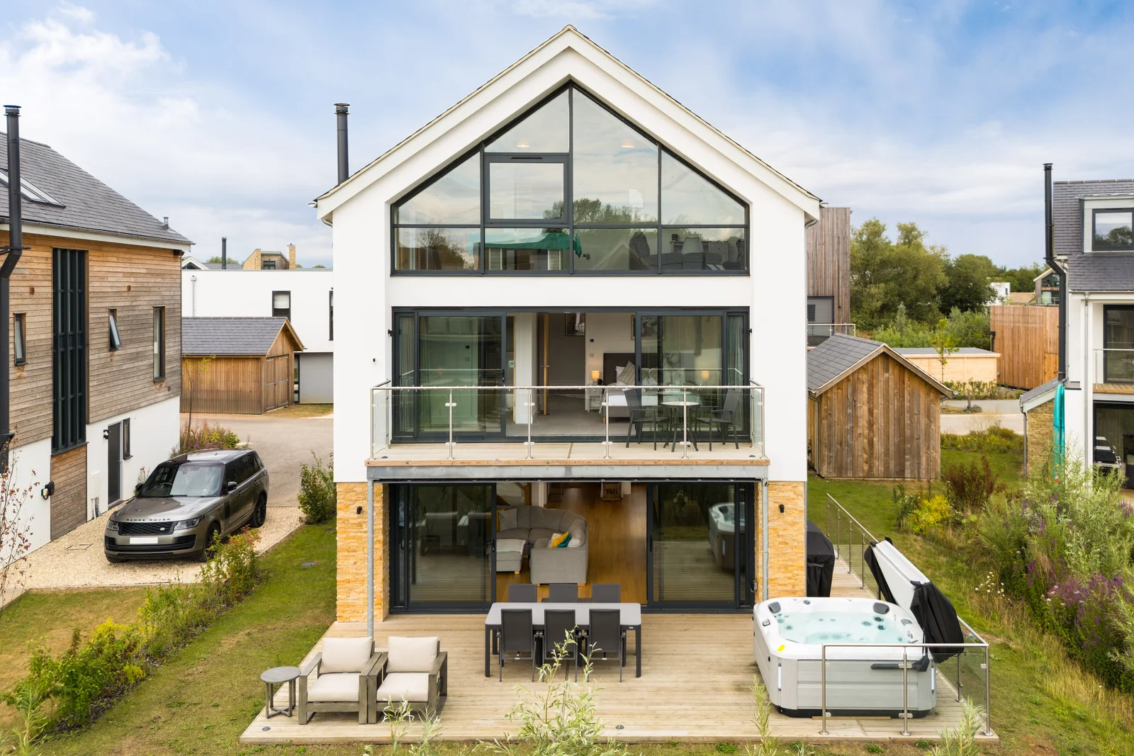 Gable fronted waterside house with two storey glazing in evening light