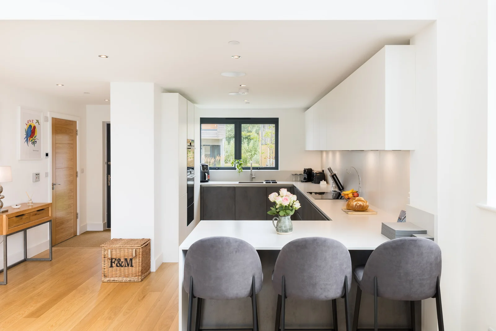 White kitchen and dining space with wide glazed doors onto a waterside terrace